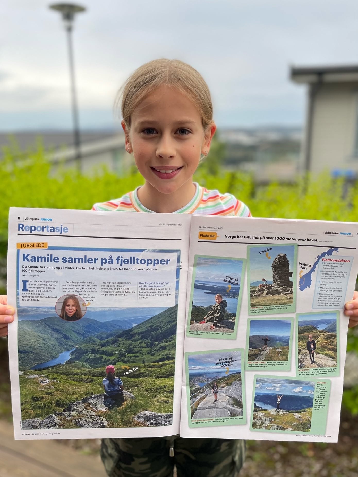 Jente som holder opp Aftenposten Junior med reportasjen «Kamile samler på fjelltopper».
