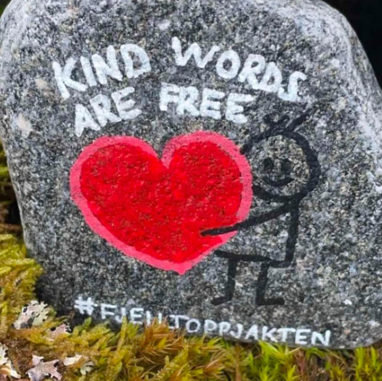 Malt stein på en fjelltopp med teksten «Kind words are free» og #fjelltoppjakten.